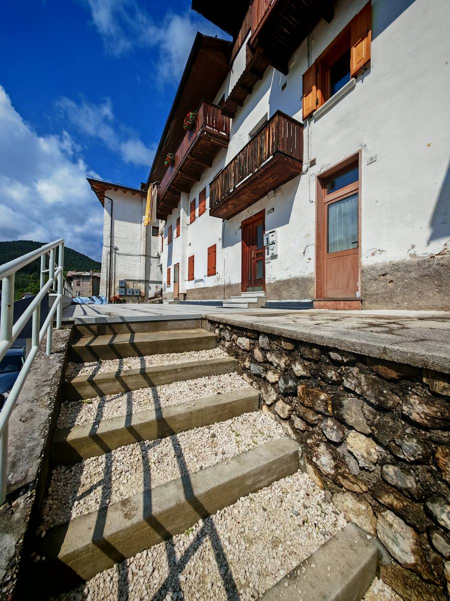 Ingresso laterale con scalinata in pietra e balcone del palazzo Rium Dolomiti
