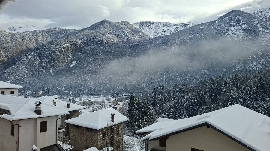 Vista invernale dal balcone di Rium Dolomiti: tetti innevati e montagne sotto la neve