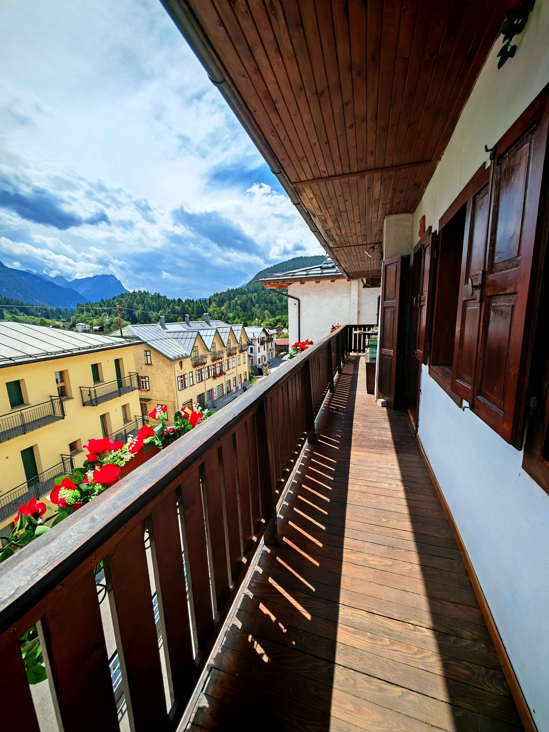 Balcone di Rium Dolomiti con gerani rossi e vista panoramica sulle Dolomiti