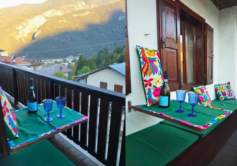 Balcone di Rium Dolomiti al tramonto con prosecco e cuscini colorati